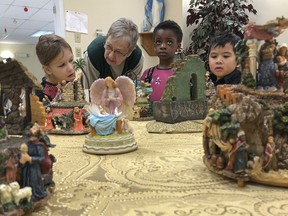 The Nativity Project Exhibition volunteer Mary Pat Byrne discusses classic music boxes, angels and nativity creche globes with École Catholique Cathédrale kindergarten students Veronica Lasso, Amarachi Egbunonu and Julius Batuta during their class's tour of the local exhibit in Kingston, Ont. on Friday, December 13, 2019.