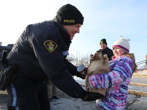 OPP Const. Steve Earle receives a bag of donations for the Morningstar Mission food bank from eight-year-old Taryn Neild outside of Giant Tiger in Napanee on Saturday, Dec. 21, 2019. The food drive was run by the Lennox and Addington County OPP Auxiliary. Meghan Balogh/The Whig-Standard/Postmedia Network