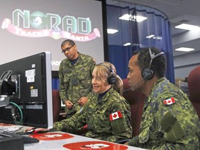 Capt. Brad Ticky, left, Aviator Diana Perry and Aviator Andre Hercules conduct a mock exercise at 22 Wing/CFB North Bay for the 64th Norad Tracks Santa event . POSTMEDIA NETWORK FILE PHOTO