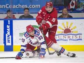Soo Greyhounds centre Alex Johnston (standing) and Kitchener Rangers winger Jonathan Yantsis battle for puck possession during OHL play at Kitchener Memorial Auditorium