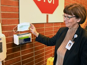 Lori Marshall, president and CEO of Chatham-Kent Health Alliance, pulls a protective mask from a box posted at one of the entrances to the Chatham Campus Jan. 27, 2020.