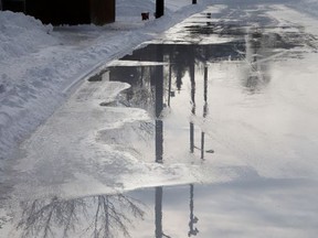 The melting ice reflects the surroundings at the Queen's Athletic Field skating oval in Sudbury, Ont. on Thursday January 2, 2020.