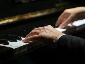Professional musician pianist hands on piano keys of a classic piano in the dark.