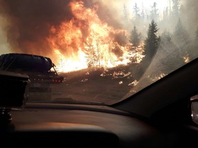 Wildfires line Highway 63 southbound as residents of Fort McMurray leave the downtown area on Tuesday May 3, 2016.  Municipalities and Metis settlements as of April 1 will be on the hook for 10 per cent of damages caused by natural disasters like floods and wildfires, says Alberta’s municipal affairs minister.