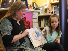 Sophia Spencer, 11, uses a butterfly pointer while talking about one of the illustrations in her newly published book, The Bug Girl (a true story) during a book-signing in February at The Book Keeper book store in Sarnia. Denise Jones, one of Sophie's teachers, is holding the book. Spencer has received an award from the Canadian Museum of Nature in Ottawa.