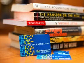 A stock photo of library cards from the Grande Prairie Public Library (GPPL) along with a stack of books.