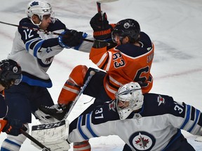 Edmonton Oilers Tyler Ennis (63) being pushed to the ice behind Winnipeg Jets goalie Connor Hellebuyck (37) by Dylan DeMelo (12) during NHL action at Rogers Place in Edmonton, March 11, 2020.