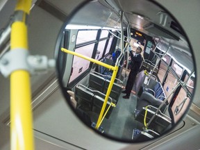 Mike, a Belleville Transit driver, is reflected in a mirror as he disinfects a bus inside the Belleville Transit bus garage. ALEX FILIPE