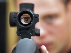 An employee looks through the scope of long gun at a gun store in Calgary, Alta.