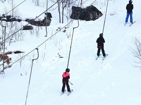 Snowboarders and skiers travel up a ski lift at the Lively Ski Hill in Lively