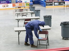 A city employee sanitizes a table and chair at the Sudbury Community Arena in Sudbury, Ont. on Monday March 23, 2020. Tables and chairs have been set up at the arena for people who need a place to eat who normally have their lunch and supper at the Samaritan Centre in Sudbury, Ont. Lunch is from 11 a.m. to 1 p.m., and supper from 5:30 p.m. to 7:30 p.m.