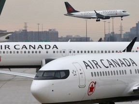 FILE PHOTO: Two Air Canada Boeing 737 MAX 8 aircrafts are seen on the ground as Air Canada Embraer aircraft flies in the background at Toronto Pearson International Airport in Toronto, Ontario, Canada, March 13, 2019.  REUTERS/Chris Helgren/File Photo ORG XMIT: FW1

NARCH/NARCH30