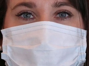 A nurse, wearing a protective mask, waits for patients.