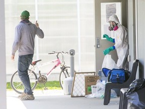 A man who just dropped off an air filter gives a thumbs up to person in full PPE at Residence 2 at Greenhill Produce in Kent Bridge, Ontario. A sign on the door states "DO NOT ENTER! This bunkhouse is under quarantine." Dozens of migrant workers that are housed in bunkhouses have been diagnosed with COVID-19. Photo shot on Tuesday April 28, 2020. Derek Ruttan/The London Free Press/Postmedia Network