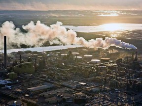 The setting sun reflects off a tailings pond behind Syncrude's oilsands upgrading facility north of Fort McMurray, Alta. in June, 2013