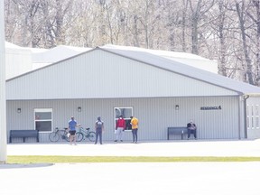 Men gather outside of Residence 4 at the Greenhill Produce in Kent Bridge, Ontario. Dozens of migrant workers that are housed in such bunkhouses have been diagnosed with COVID-19. Photo shot on Tuesday April 28, 2020. Derek Ruttan/The London Free Press/Postmedia Network