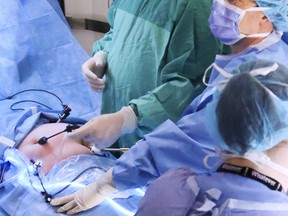 Drs. Sean McIlreath, left, and Chance Holder check a video display while operating at Belleville General Hospital in 2014. At bottom right is nurse Stephanie Williams. Scheduled surgeries at BGH are to resume Tuesday, June 2, 2020.