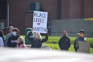 A protestor raises a sign at a passing vehicle as traffic flows by the Sudbury Courthouse on Sunday.