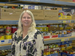 Executive Director Lori McRitchie poses with some of the stockpiled canned goods at the Airdrie Food Bank on Thurs., March 29, 2018.