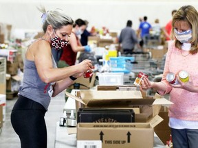 Adina Rainbird, left, and Sue Cummings box canned goods donated during the May 16 Miracle at Thames Campus Arena in Chatham, Ont., on Thursday, May 21, 2020. Mark Malone/Chatham Daily News/Postmedia Network