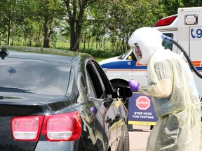 Lee Chantrell, an advanced care paramedic with the County of Renfrew, speaks to the occupants of a vehicle during the a pop-up drive-thru testing clinic for COVID-19 in the parking lot of the Renfrew County District Health Unit Pembroke office May 27. Tina Peplinskie