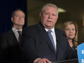 Premier Doug Ford (C) answers a question as Christine Elliott, (R) Deputy Premier and Minister of Health and Peter Bethlenfalvy, President of the Treasury Board (L) listen at a media conference at the Chateau Laurier in Ottawa.