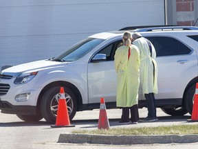 Health care workers assess a person at the Carling Heights Optimist Community Centre COVID-19 assessment centre in London, Ont. on Monday April 6, 2020. Nine cars were lined up when the centre opened shortly after 11:00am. Derek Ruttan/The London Free Press/Postmedia Network