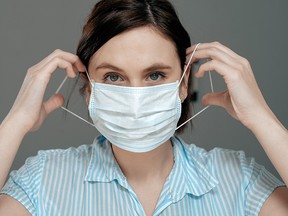 A woman puts on a mask in this stock image.