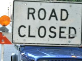 A woman walks past a "road closed" sign