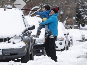 Good Samaritans Jim Lim and his son, McKinley, clear snow from a neighbour’s car in Toronto last winter. Stan Behal/Toronto Sun/Postmedia Network