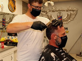 Yvan Michaud takes a bit off the top for Rusty Shackleford, Friday, at Ray's Barber Shop on Main Street. Michaud had already served about 17 customers after the shop opened for the first time in three months, and there were plenty more waiting their turns.
PJ Wilson/The Nugget
