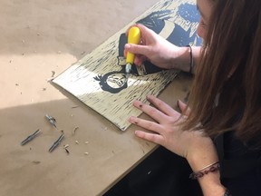 A student from Ms. Johnston's Grade 12 class at St. Mary's Catholic High School cuts a design into lino to create a printing plate. The class worked with London artist Jessica Woodward on a collaborative surrealism printmaking project. (Woodstock Art Gallery)