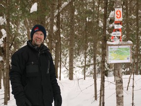 Chris Holmes poses in front of one of the trails he helped create and maintain. Submitted Photo