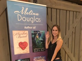 Forest fantasy writer Melina Douglas poses in front of a poster featuring the covers of her four novels. Handout/Sarnia This Week