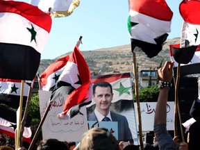 People wave Syrian national flags and pictures of President Bashar al-Assad as they gather for a demonstration in support of Assad and against US sanctions on the country, in the capital Damascus on June 11, 2020. - Syria's economy has been battered by nine years of war compounded by a financial crisis in neighbouring Lebanon, which had served as a conduit to bring dollars into government-held areas despite international sanctions. In recent days the value of the Syrian pound on the black market has tumbled from one record low to the next, with the government blaming the unofficial devaluation on US sanctions and exchange rate "manipulation". LOUAI BESHARA/AFP via Getty Images)