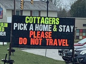 A sign in Sauble Beach, seen in this file photo from April, asks cottagers avoid travelling back and forth between their permanent and summer homes.