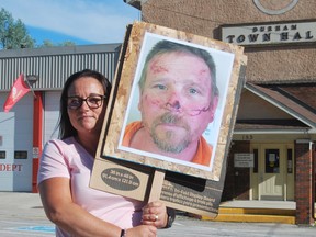 Cheryl Hillier, wife of Casey Hillier, held a sign at Thursday’s protest with a photo of her husband that shows him with cuts and bruising on his face and forehead. KEITH DEMPSEY