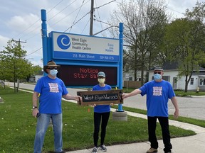 West Elgin Acquired Brain Injury Support Group facilitators Doug Walker, Shelly Vergeer and Don Bobie hold up a sign for their team, West Elgin Warriors, for Mike’s 5K Superhero Walk for Brain Injury.