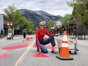 Micheline Lambert, Owner/Designer of F2 Floral Fashion, paints hearts six meters apart along the new pedestrian area on Main Street in Canmore on June 16. The goal of the design initiative called Joining Hearts Responsibility acts as a symbolic reminder of the COVID19 social distancing protocols while bringing people together safely. Photo Marie Conboy.