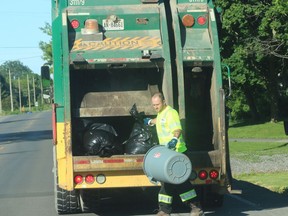 A Waste Management Canada employee collects garbage along County Road 3 in Ameliasburgh Friday morning. Since March 26, the County allowed residents to put out one untagged bag of garbage per week., but as of July 1, County residents will have to tag all garbage for curbside pickup. BRUCE BELL