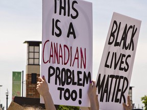 People hold signs during the protest in Harmony Square on Thursday, June 4, 2020, in Brantford, Ont. Brian Thompson