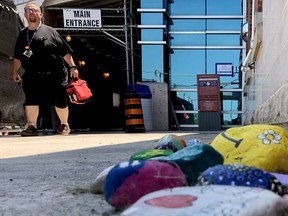 Ian Prettejohn, who works in stores at Brockville General Hospital, walks past a display of painted rocks paying tribute to front-line workers by the hospital's entrance on Friday afternoon. (RONALD ZAJAC/The Recorder and Times)