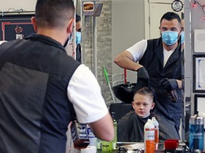 Moe Charanek cuts 12 year-old Cory Flaig's hair at the Six Barbers barber shop in Calgary, Alta., on Monday, May 25, 2020. After about two months, Calgarians could get haircuts again with barbers and stylists operating with COVID-19 precautions.