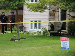 Sarnia police officers are shown Friday outside a home in Bright's Grove, during an investigation into a shooting.