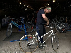 Mike Pomery of Yellow Bike Action - Kingston works on a bike at the agency's warehouse facility in a barn on the Memorial Centre grounds on Thursday. (Elliot Ferguson/The Whig-Standard)