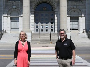 Ruth Wood, chair for Kingston Pride, and Gilles Charette, executive director for HIV/AIDS Regional Services Kingston, stand in front of the crosswalk in front of City Hall, painted rainbow colours to mark June as Pride month. (Meghan Balogh/The Whig-Standard)