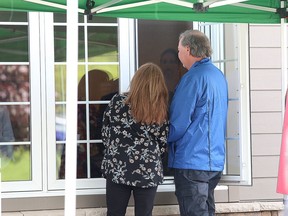Mourners meet with family members of a loved one through a window during a drive-through visitation at the Gordon F. Tompkins Funeral Home on Davis Drive in Kingston on Wednesday. (Ian MacAlpine/The Whig-Standard)