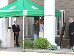 Mourners meet with family members of a loved one through a window during at drive-through visitation at Gordon F. Tompkins Funeral Home on Davis Drive in Kingston on June 3, 2020.