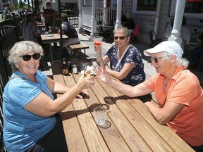 Kathy Hickey, left, Lil Hoover and Donna Brown toast on the patio of Tir Nan Og on Friday afternoon. With Stage 2 of the COVID-19 pandemic reopening protocol allowing for the easing of some restrictions, outdoor patios in Kingston were able to reopen on Friday. (Ian MacAlpine/The Whig-Standard)