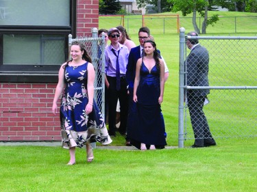 Naomi Jersch, J.T. Foster's valedictorian, walks towards the tent on the lawn north of the school where each of the three graduation ceremonies took place Saturday.